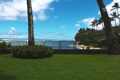 Bild på en stor tropisk bakgård, med en stödmur och naturstensplattor