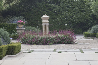 Réalisation d'un grand jardin à la française avant méditerranéen avec un point d'eau, une exposition ensoleillée et des pavés en pierre naturelle.