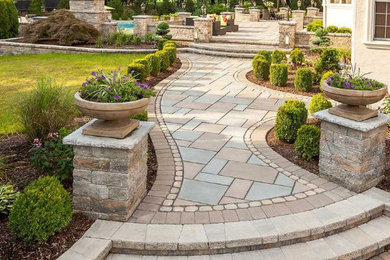 This is an example of a large traditional back formal partial sun garden for spring with a garden path and natural stone paving.