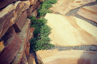 Imagen de jardín de secano grande en verano en ladera con muro de contención, exposición total al sol y adoquines de piedra natural