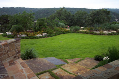 Design ideas for a mid-sized traditional partial sun backyard stone retaining wall landscape in Austin.