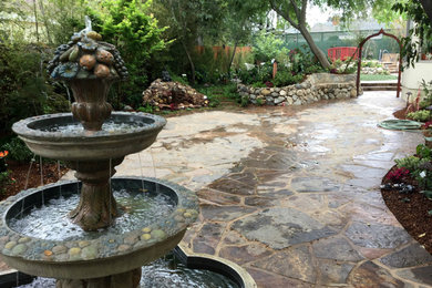Imagen de jardín tropical grande en patio con jardín francés, estanque, exposición parcial al sol y adoquines de piedra natural