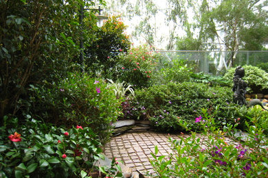 Modelo de jardín tradicional de tamaño medio en verano en patio trasero con jardín francés, estanque, exposición parcial al sol y adoquines de piedra natural