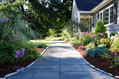 This is an example of a mid-sized traditional partial sun front yard stone landscaping in Boston for summer.