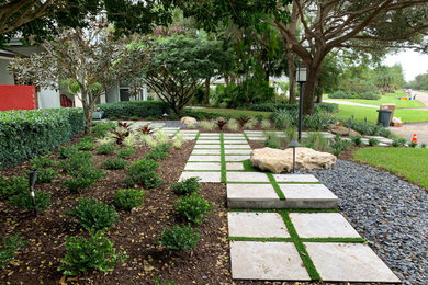 This is an example of a mid-sized transitional partial sun front yard stone landscaping in Miami.