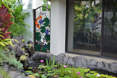 ハワイにある中くらいなトロピカルスタイルのおしゃれな裏庭 (池、日向) の写真