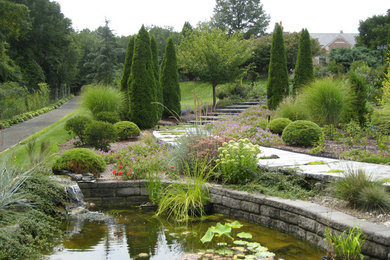 Modelo de jardín actual extra grande en verano en patio delantero con exposición parcial al sol y adoquines de piedra natural