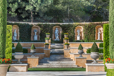 На фото: огромный регулярный сад на склоне в средиземноморском стиле с покрытием из каменной брусчатки