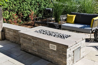 This is an example of a medium sized modern back partial sun garden for spring in Ottawa with natural stone paving.