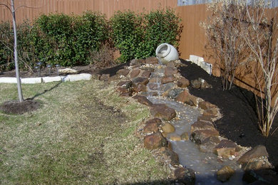 This is an example of a large partial sun backyard mulch water fountain landscape in Austin.