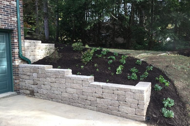 This is an example of a mid-sized transitional full sun front yard mulch retaining wall landscape in Other.