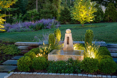 Imagen de jardín tradicional grande en verano en patio trasero con fuente, exposición parcial al sol y adoquines de piedra natural