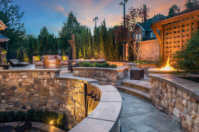 This is an example of a large rustic backyard concrete paver landscaping in Salt Lake City with a fire pit.