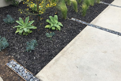 This is an example of a contemporary front yard concrete paver driveway in Orange County.