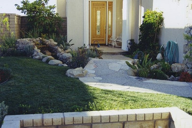 This is an example of a large full sun garden in Los Angeles with natural stone paving.
