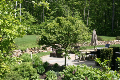 Ejemplo de jardín clásico de tamaño medio en primavera en patio trasero con exposición total al sol y adoquines de piedra natural