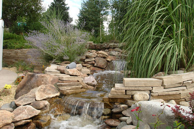 Photo of a mid-sized craftsman full sun backyard stone water fountain landscape in Denver for summer.