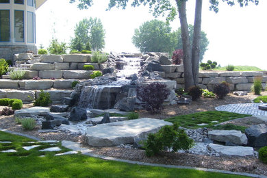 Ejemplo de jardín grande en patio trasero con exposición reducida al sol, adoquines de piedra natural y estanque