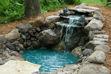 Photo of a mid-sized full sun backyard stone water fountain landscape in Grand Rapids.