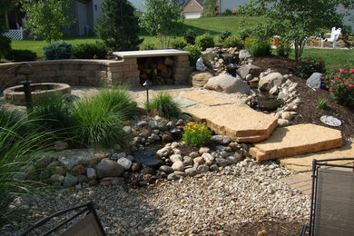 Imagen de jardín tradicional grande en patio trasero con fuente, exposición parcial al sol y adoquines de piedra natural