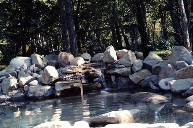 Design ideas for a mid-sized full sun backyard stone water fountain landscape in Calgary.