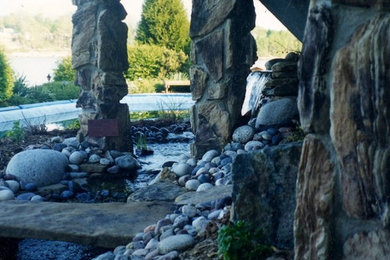 Inspiration for a large traditional partial sun backyard stone water fountain landscape in Other.