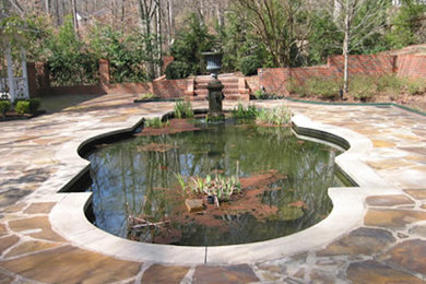 Imagen de jardín en patio trasero con fuente y adoquines de piedra natural