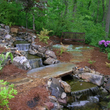 Waterfall and stone bridge over to garden bench