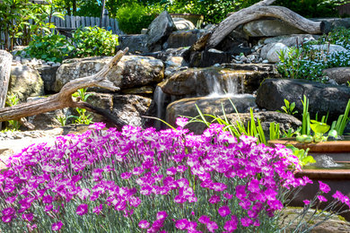 Ejemplo de jardín rústico de tamaño medio en primavera en patio trasero con adoquines de piedra natural y fuente