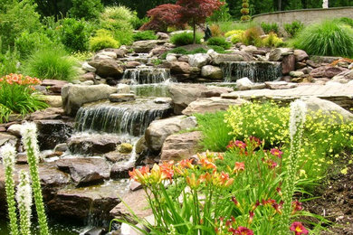Ejemplo de jardín clásico grande en verano en patio trasero con exposición parcial al sol y adoquines de piedra natural
