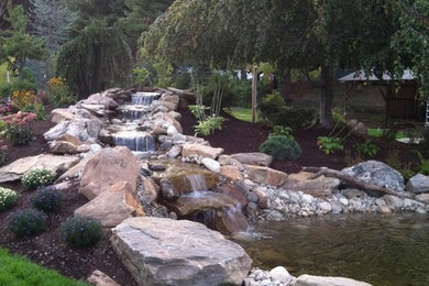 Photo of a sloped garden in New York with a water feature.