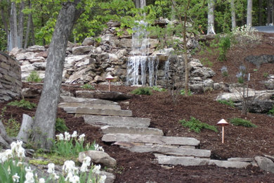 Modelo de jardín tradicional renovado grande en ladera con fuente y adoquines de piedra natural