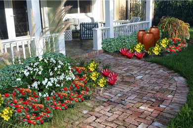 Foto de jardín exótico de tamaño medio en patio delantero con jardín francés, fuente, exposición total al sol y adoquines de ladrillo