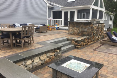 Photo of a mid-sized traditional partial sun backyard concrete paver landscaping in Boston with a fire pit.