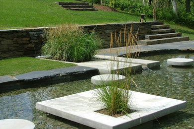 Foto de jardín contemporáneo de tamaño medio en primavera en patio trasero con fuente, exposición parcial al sol y adoquines de piedra natural