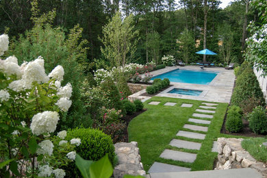 Immagine di un giardino classico esposto in pieno sole dietro casa e di medie dimensioni con un muro di contenimento e pavimentazioni in pietra naturale