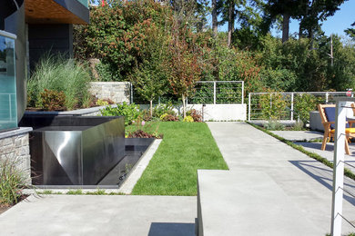 This is an example of a mid-sized contemporary full sun front yard concrete paver water fountain landscape in Vancouver.