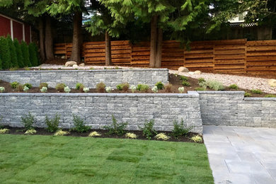 Inspiration for a mid-sized modern backyard concrete paver retaining wall landscape in Vancouver.
