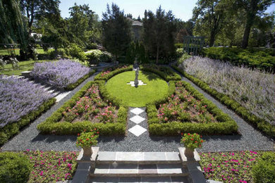 Imagen de jardín tradicional grande en verano en patio con jardín francés, exposición total al sol y adoquines de piedra natural