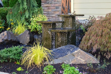 Photo of a small eclectic full sun front yard mulch water fountain landscape in Seattle.