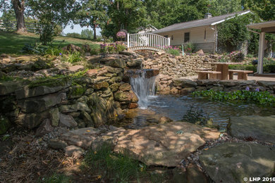 Cette photo montre un grand jardin arrière chic l'été avec un point d'eau, une exposition partiellement ombragée et des pavés en pierre naturelle.
