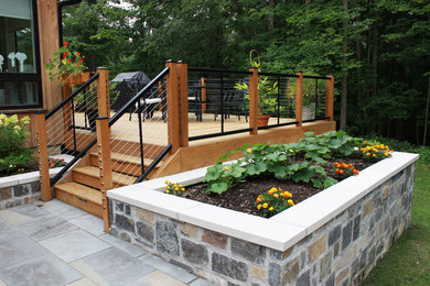 Photo of a mid-sized contemporary full sun hillside stone and metal fence retaining wall landscape in Columbus for summer.