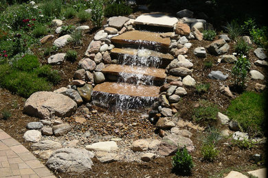 Modelo de jardín en patio trasero con cascada y piedra decorativa