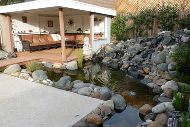 Modelo de jardín minimalista de tamaño medio en patio trasero con fuente, exposición parcial al sol y adoquines de piedra natural