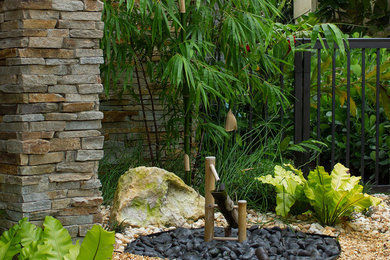 Modelo de jardín pequeño en patio delantero con fuente, exposición reducida al sol y adoquines de piedra natural