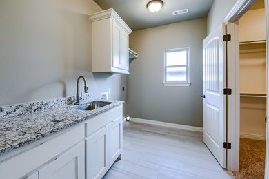 Mid-sized transitional single-wall porcelain tile and gray floor dedicated laundry room photo in Other with an undermount sink, shaker cabinets, white cabinets, granite countertops, gray walls and multicolored countertops
