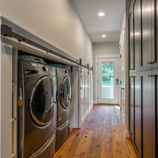 Small cottage single-wall medium tone wood floor and brown floor laundry closet photo in Seattle with shaker cabinets, black cabinets, gray walls and a side-by-side washer/dryer