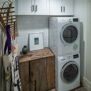 Example of a small cottage brown floor laundry closet design in Denver with shaker cabinets, white cabinets, wood countertops, white walls and a stacked washer/dryer