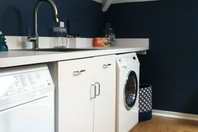 リッチモンドにあるお手頃価格の中くらいなトランジショナルスタイルのおしゃれな家事室 (シングルシンク、白いキャビネット、ラミネートカウンター、青い壁、コルクフローリング、左右配置の洗濯機・乾燥機) の写真