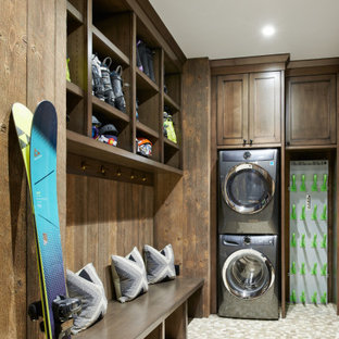 Exemple d'une buanderie montagne en L multi-usage avec un placard à porte shaker, des portes de placard en bois sombre, des machines superposées et un sol beige.